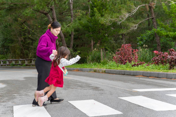  Женщина помогает ребёнку перейти дорогу, демонстрируя безопасность.